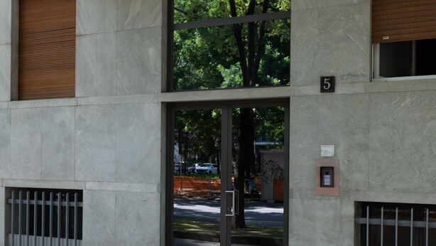 A building entrance with a glass door, a number '5' sign, and a small plaque on the wall.