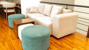 Un salon moderne avec un canapé beige, deux poufs turquoise et une table basse en bois.