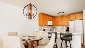 A modern kitchen with wooden cabinets, a central island, and bar stools. - Community Pool Near Lake Como Interlaken for 6 (Lake Geneva)