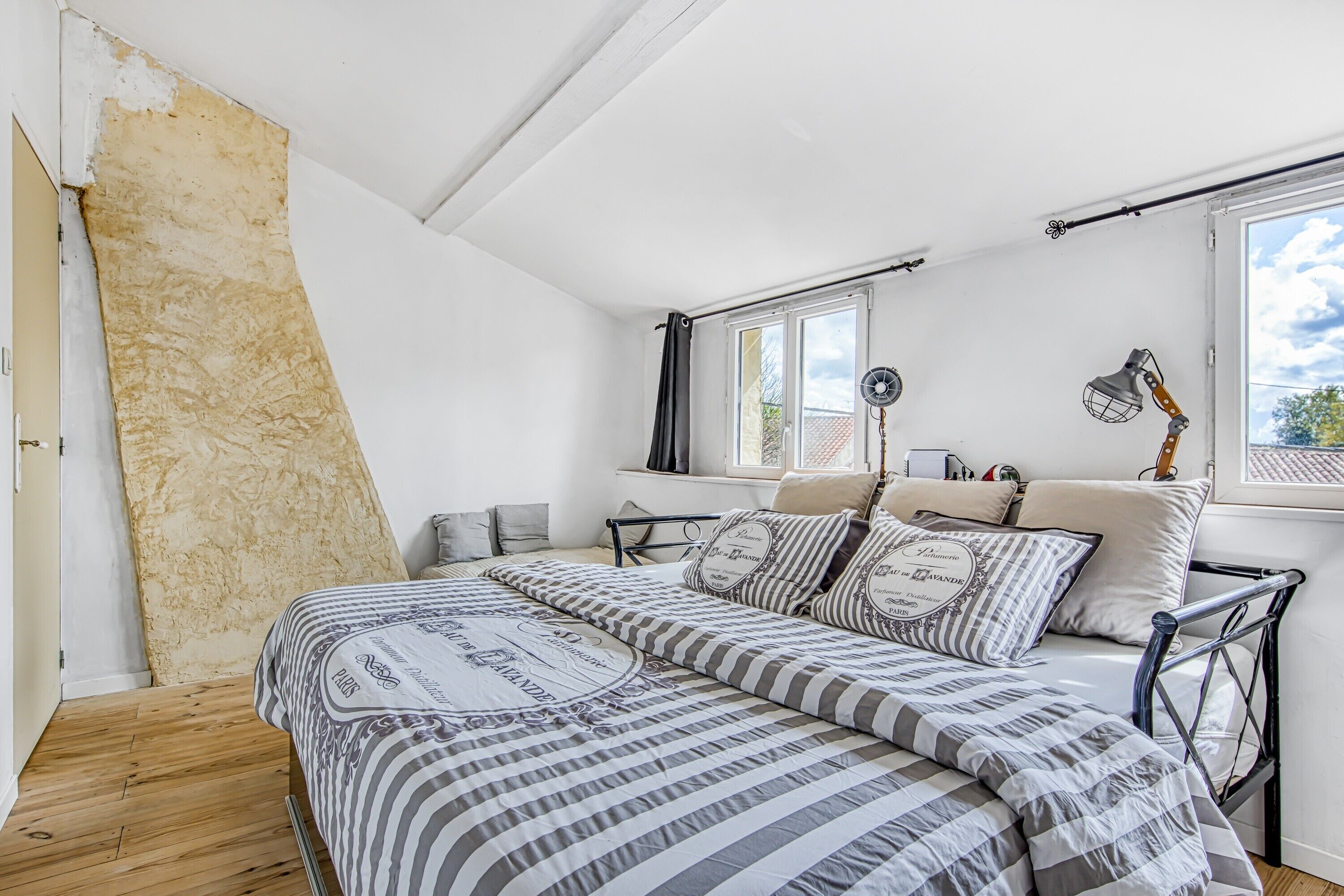 Een slaapkamer met een bed, een raam, een ventilator en een lamp.