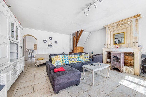 Un salon avec un canapé, une table basse, une cheminée et un escalier.