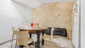 A dining area with a round table, chairs, and a stone wall.