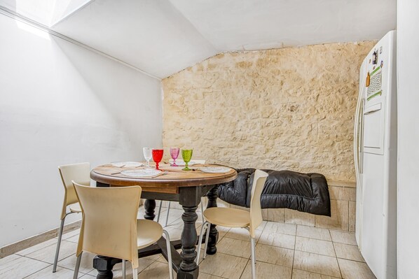 Un comedor con una mesa redonda, sillas y una pared de piedra.