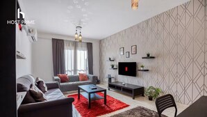 En moderne stue med sofa, sofabord, fjernsyn og pynt.