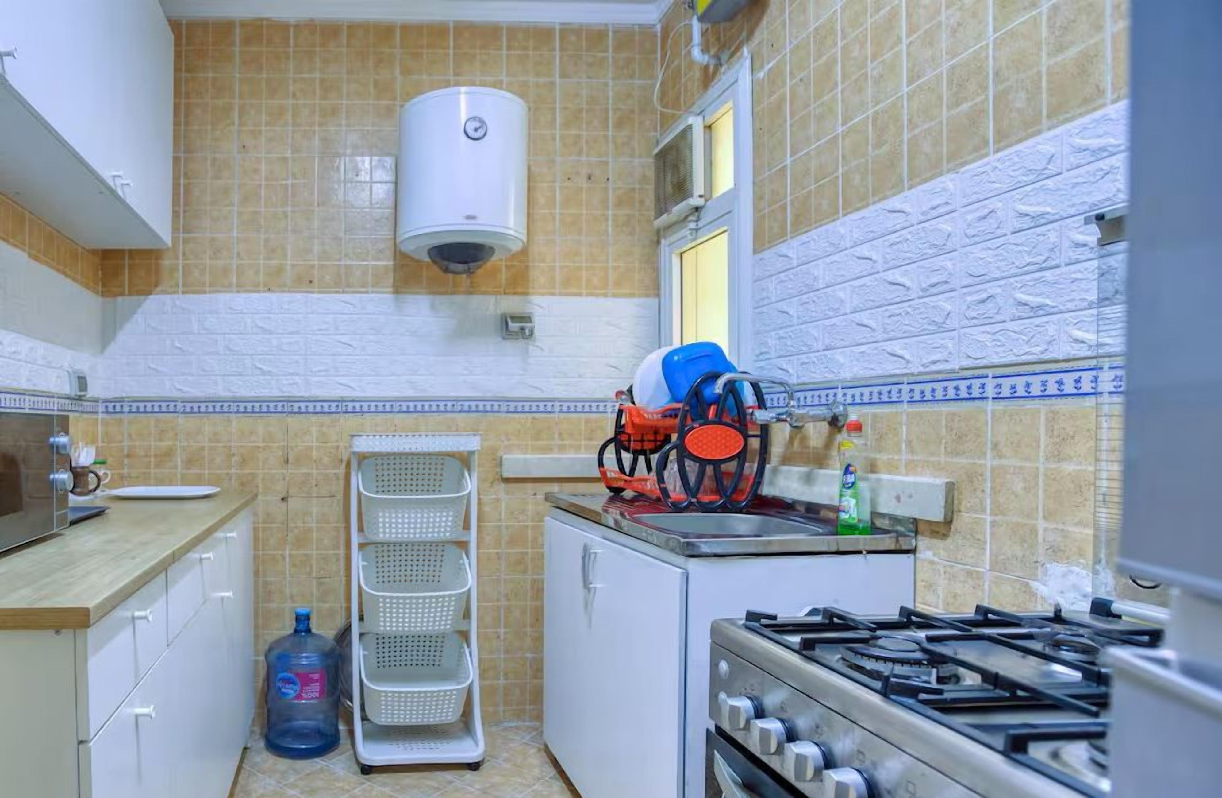 A compact kitchen with a microwave, gas stove, and a water dispenser.