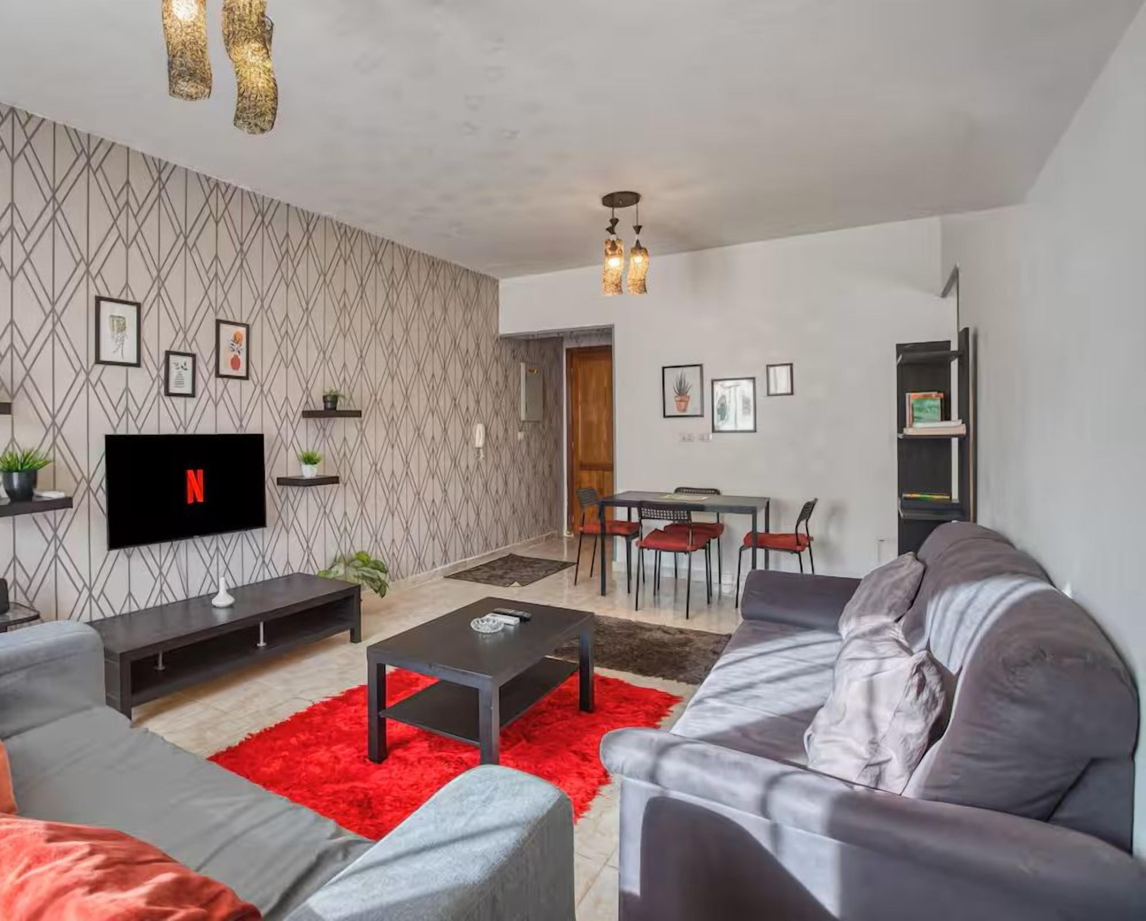 Un salon moderne comprenant un téléviseur, des canapés, une table basse et un coin repas.