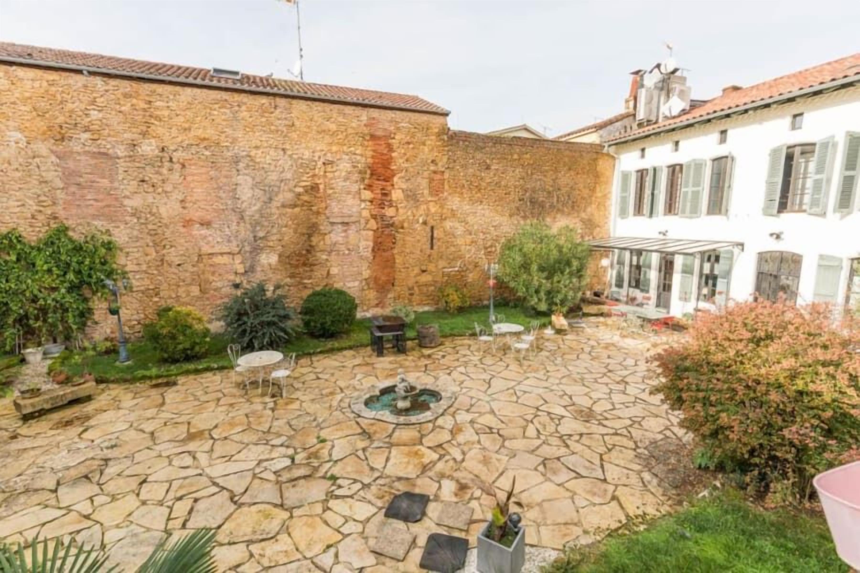A courtyard with stone flooring, a fountain, and outdoor seating.