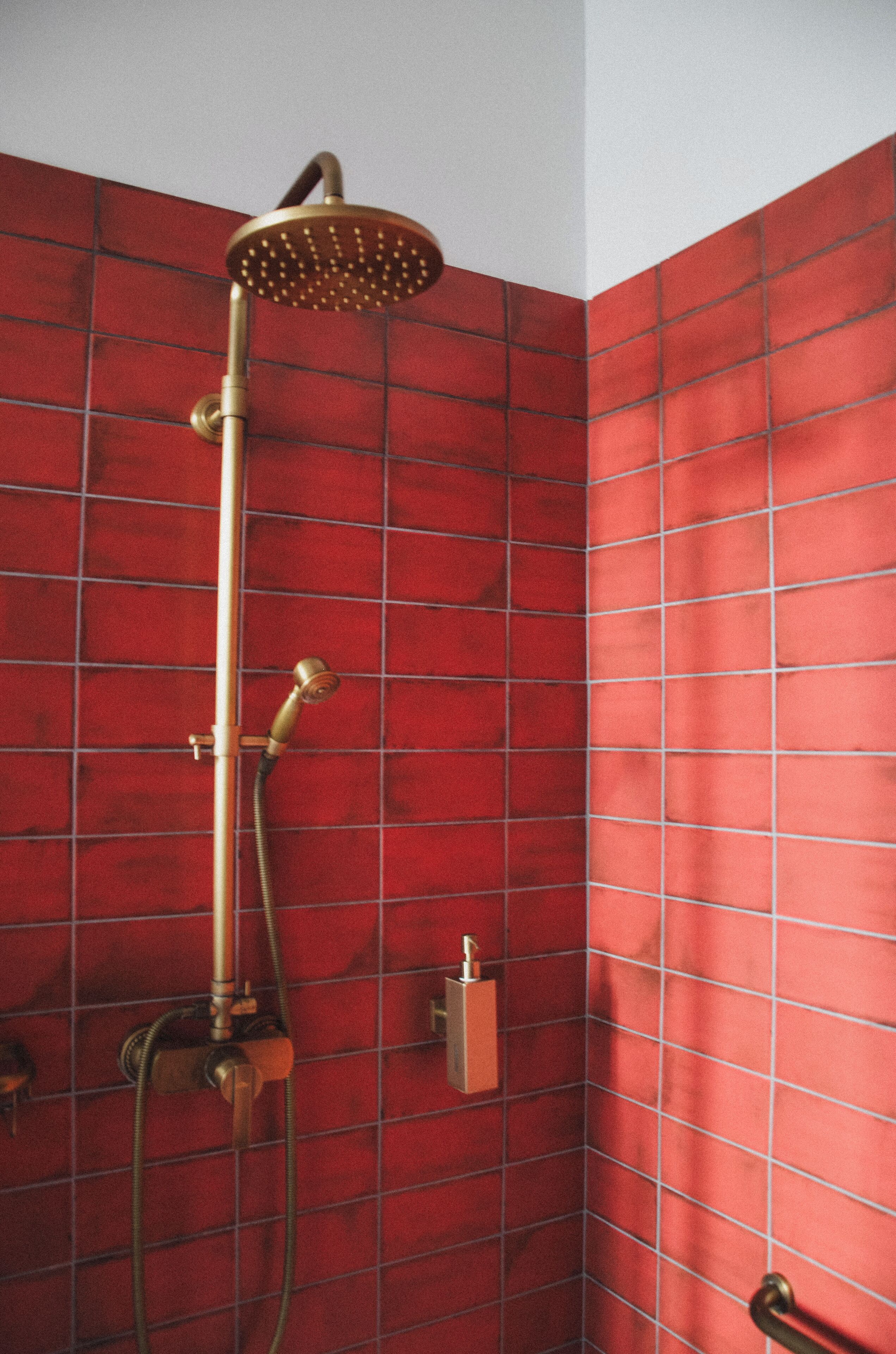 Una ducha con cabezal de ducha de mano y mandos en la pared.