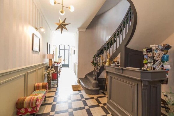 A hallway with a checkered floor, a bench, a staircase, and a wall with framed pictures. - La Maison d'Augustin (Mont-de-Marsan)