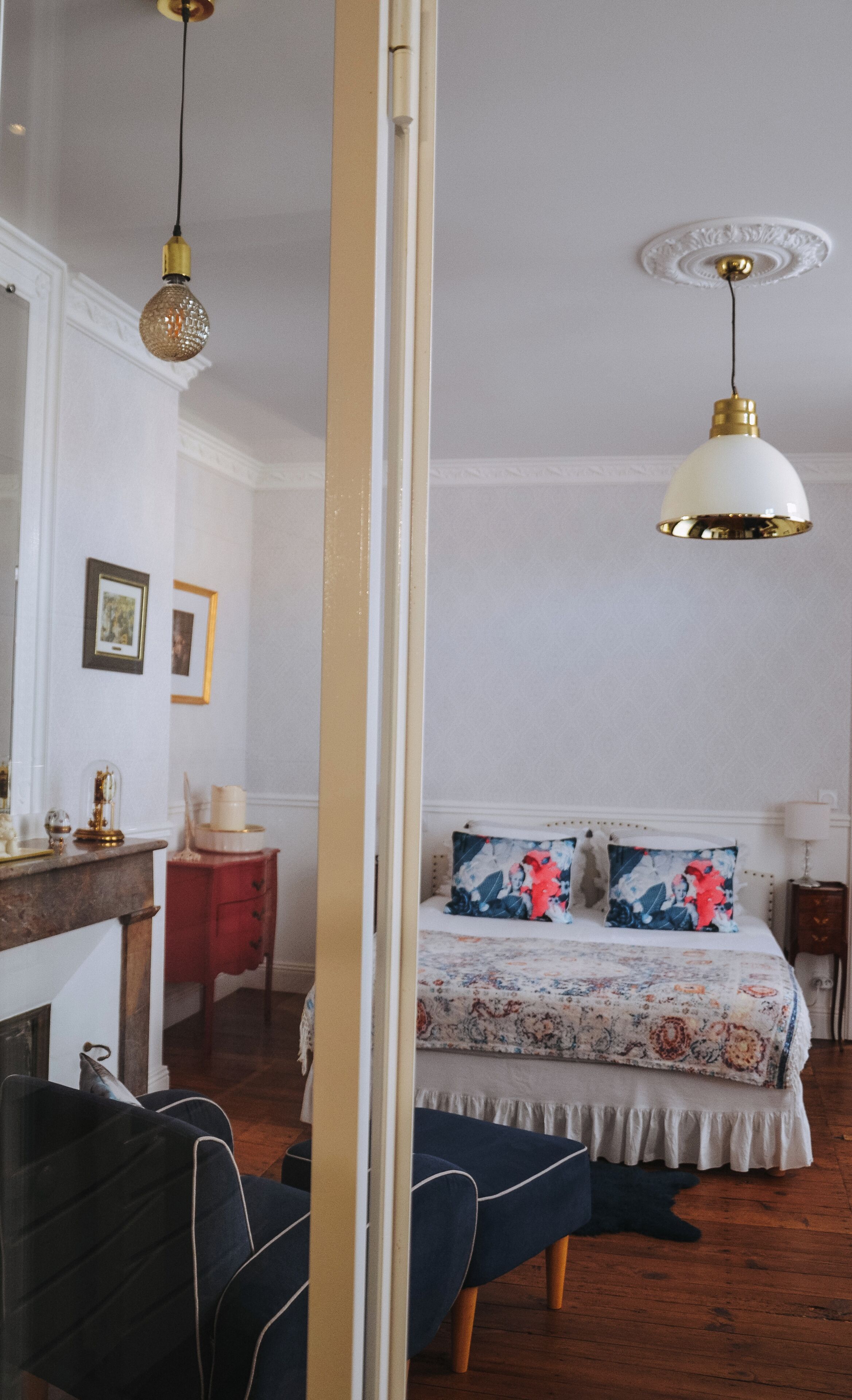 A bedroom with a bed, a nightstand, a chair, a dresser, and a mirror.