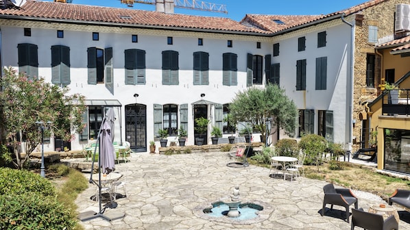 Un patio con suelo de piedra, mobiliario exterior y una fuente.