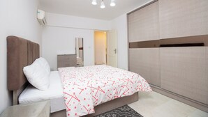 Un dormitorio con cama, armario, mesita de noche, espejo y lámpara en el techo.