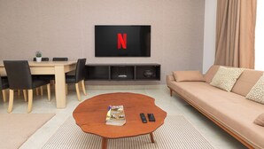 Una sala de estar moderna con una mesa redonda, un sofá, un televisor montado en la pared y un comedor con sillas y una mesa.