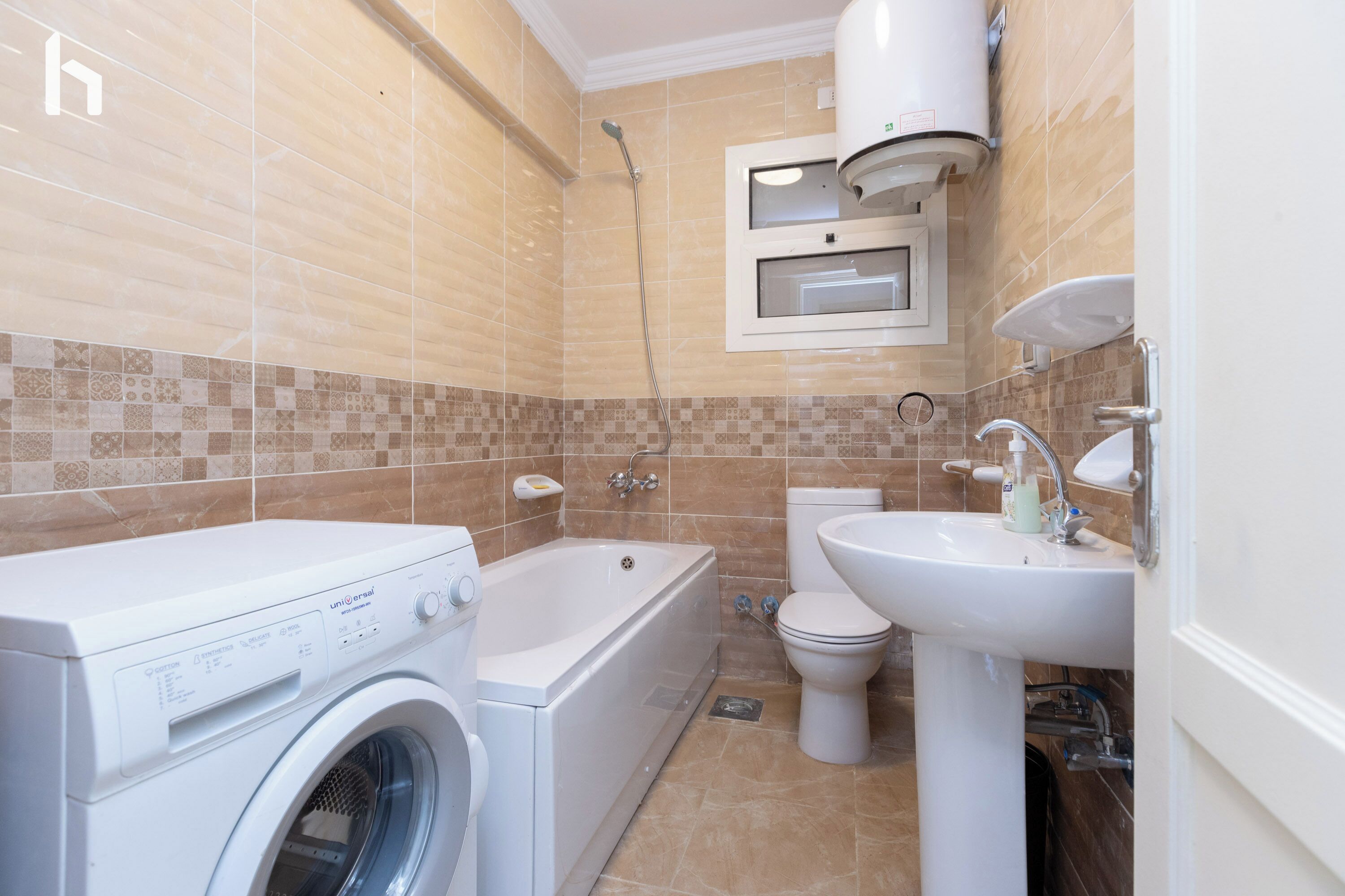 Une salle de bain moderne équipée d’un lave-linge, d’une baignoire, de toilettes et d’un lavabo.