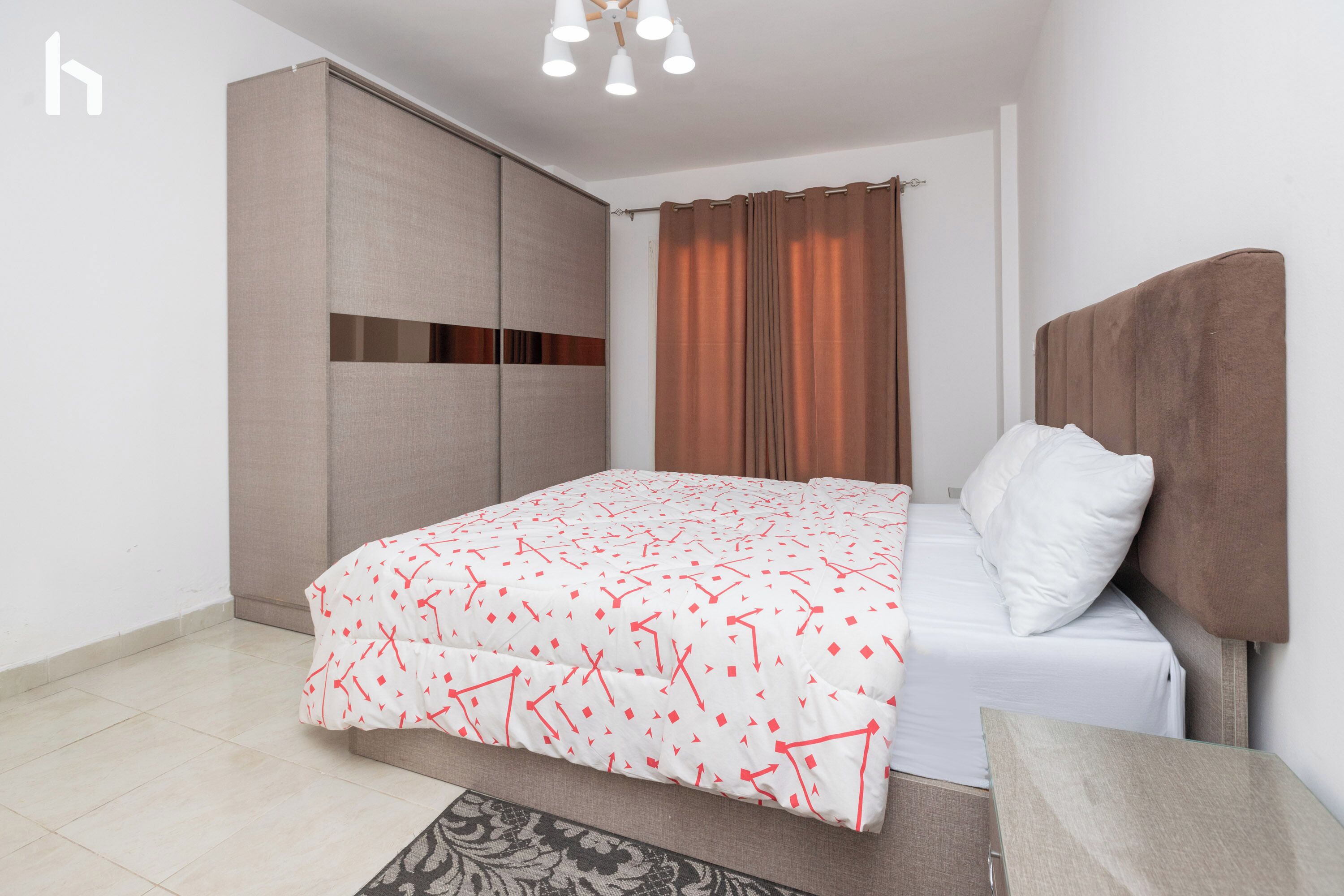 A bedroom with a bed, a wardrobe, a curtain, and a ceiling light fixture.