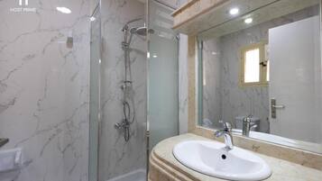 A bathroom with a glass-enclosed shower, a white sink, and a large mirror.