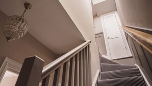 A staircase with a striped carpet, a white door, and a crystal chandelier. - Herdwick Cottage, Stylish 3 bed, Central Ambleside (Ambleside)