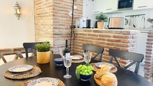 Et spisebord dækket med tallerkener, bestik, en vinflaske, glas og en skål med druer.