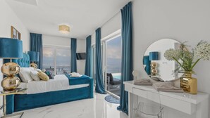 Quarto moderno com cama, penteadeira e uma grande janela com cortinas.