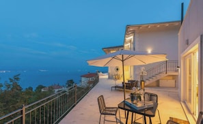 A balcony with a table, chairs, and an umbrella, overlooking a coastal view. - Villa Lauriana Nearby Opatija - Crovillas (Lovran)