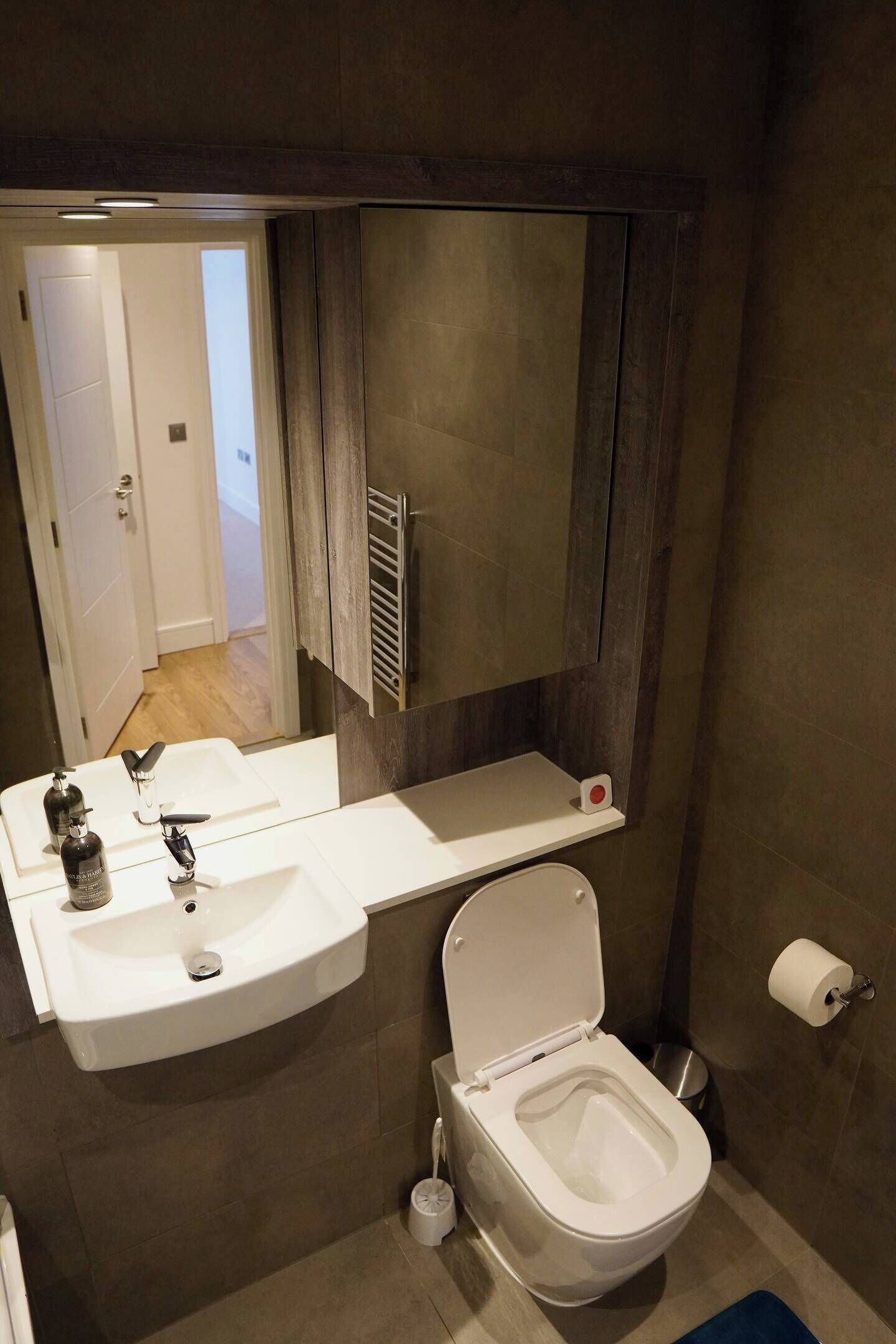 Une salle de bain avec un lavabo blanc, des toilettes, un miroir et un porte-serviettes.