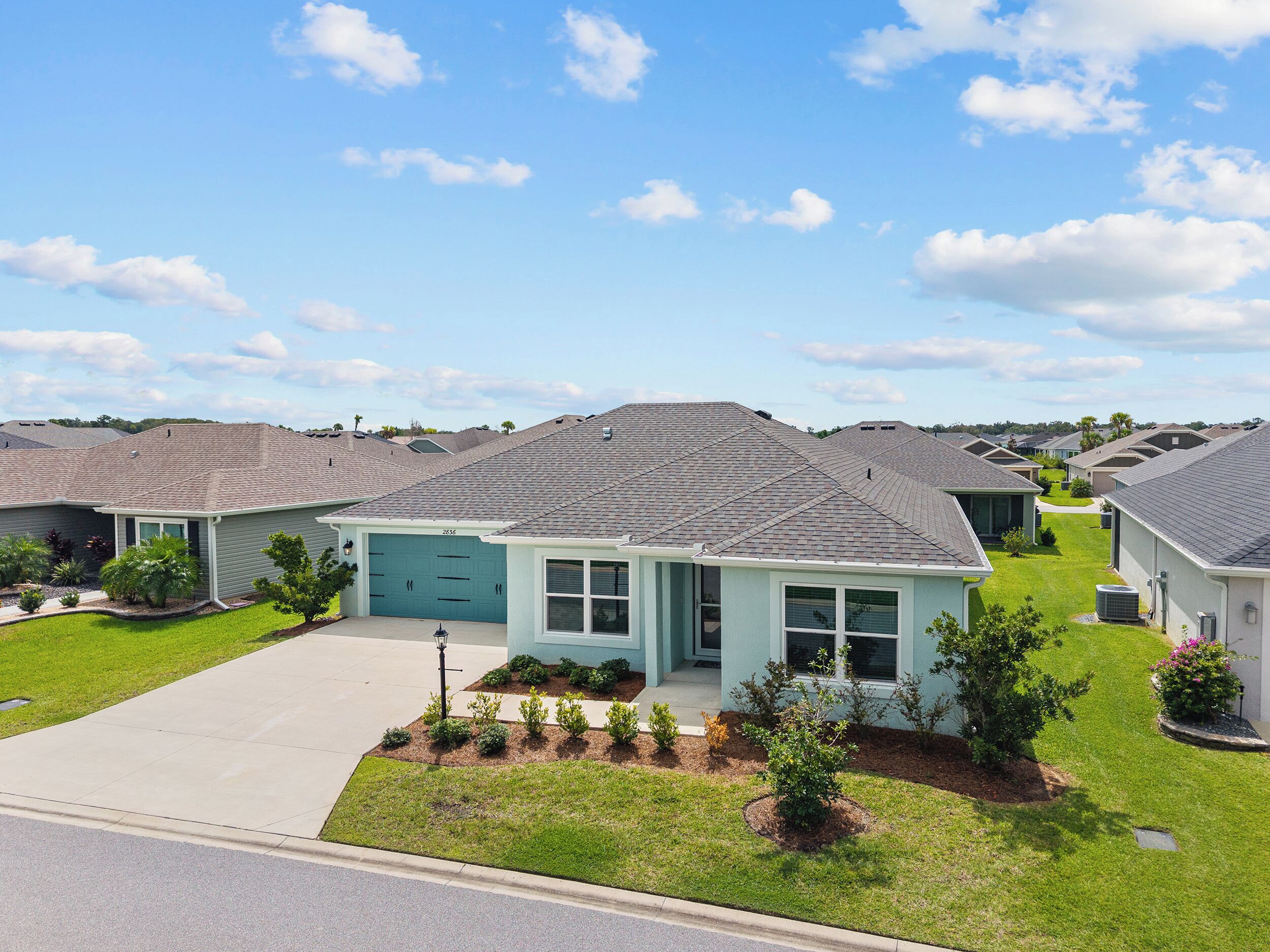 A residential neighborhood with single-family homes, a well-maintained lawn, and a clear sky.