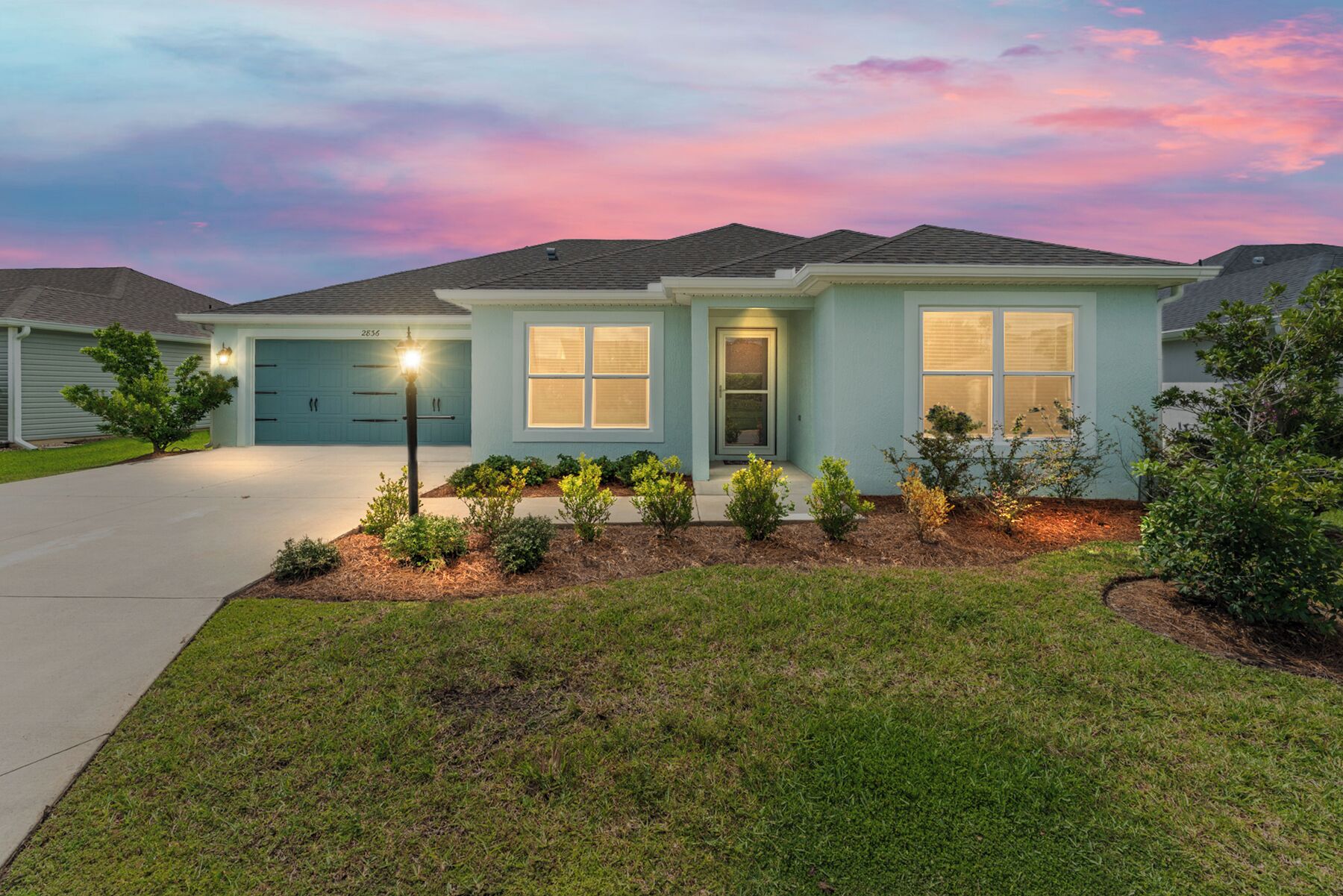 A single-story house with a light blue exterior, a front porch, and a well-maintained lawn.
