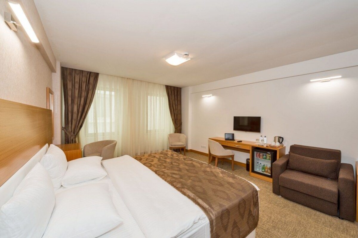Une chambre d’hôtel équipée d’un lit, d’un bureau, d’une chaise, d’un canapé, d’une télévision et d’un mini-bar.