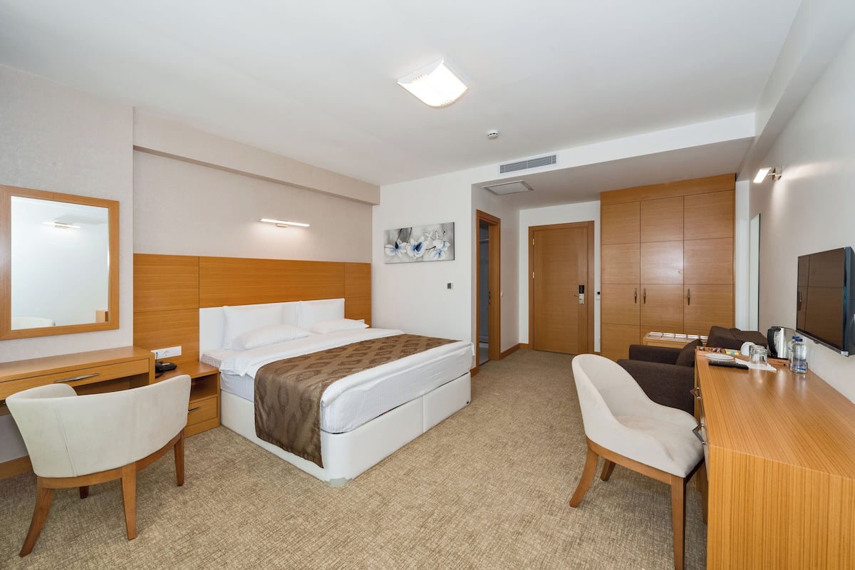 Habitació d'hotel amb un llit, una taula, dues cadires, una televisió i un armari.