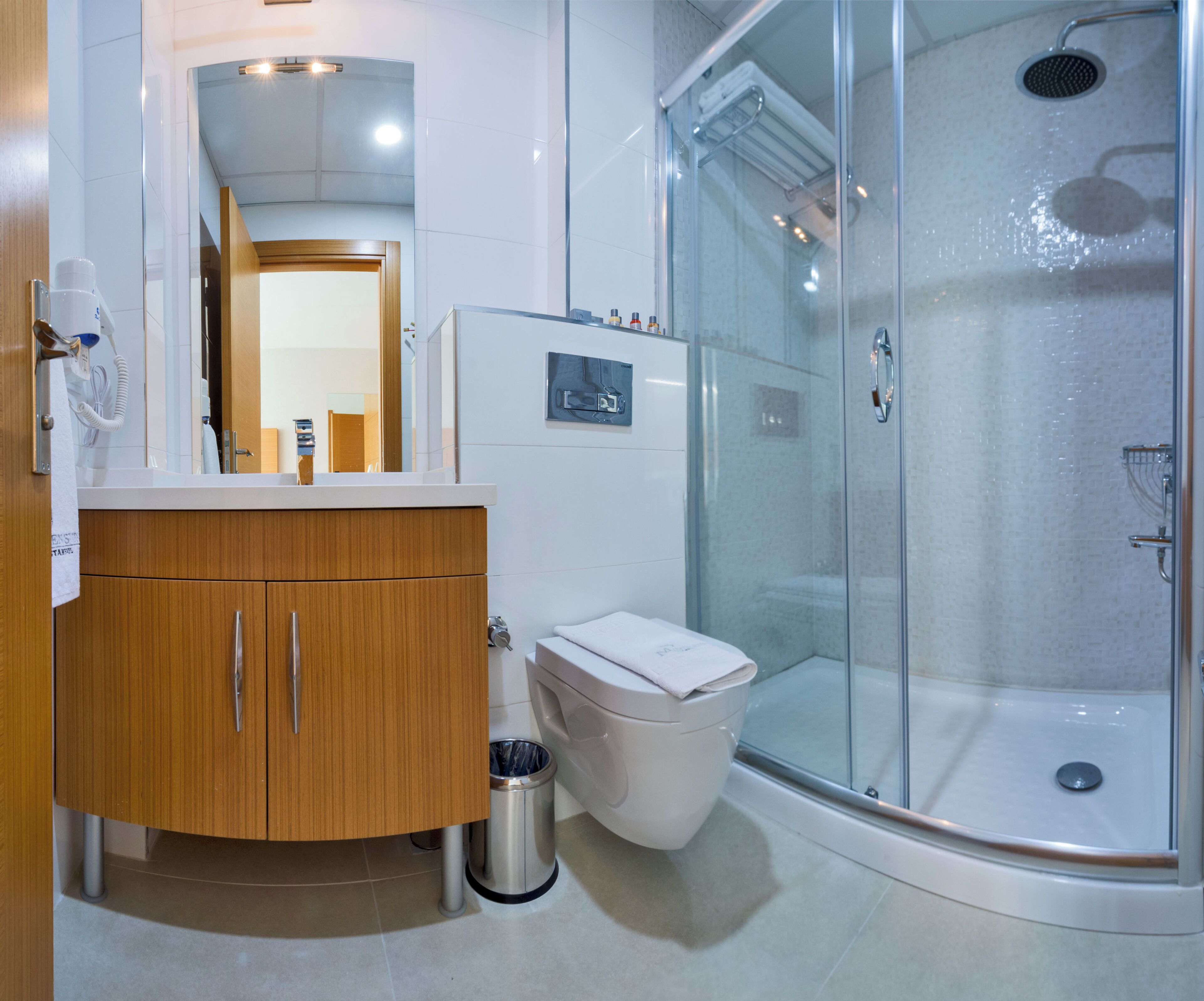 A modern bathroom with a glass-enclosed shower, a wooden vanity, and a toilet.