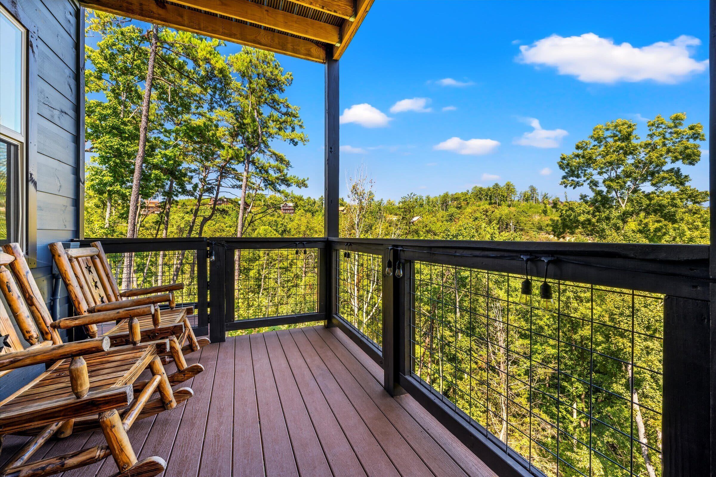 Une terrasse en bois avec des chaises longues et une vue sur une forêt.