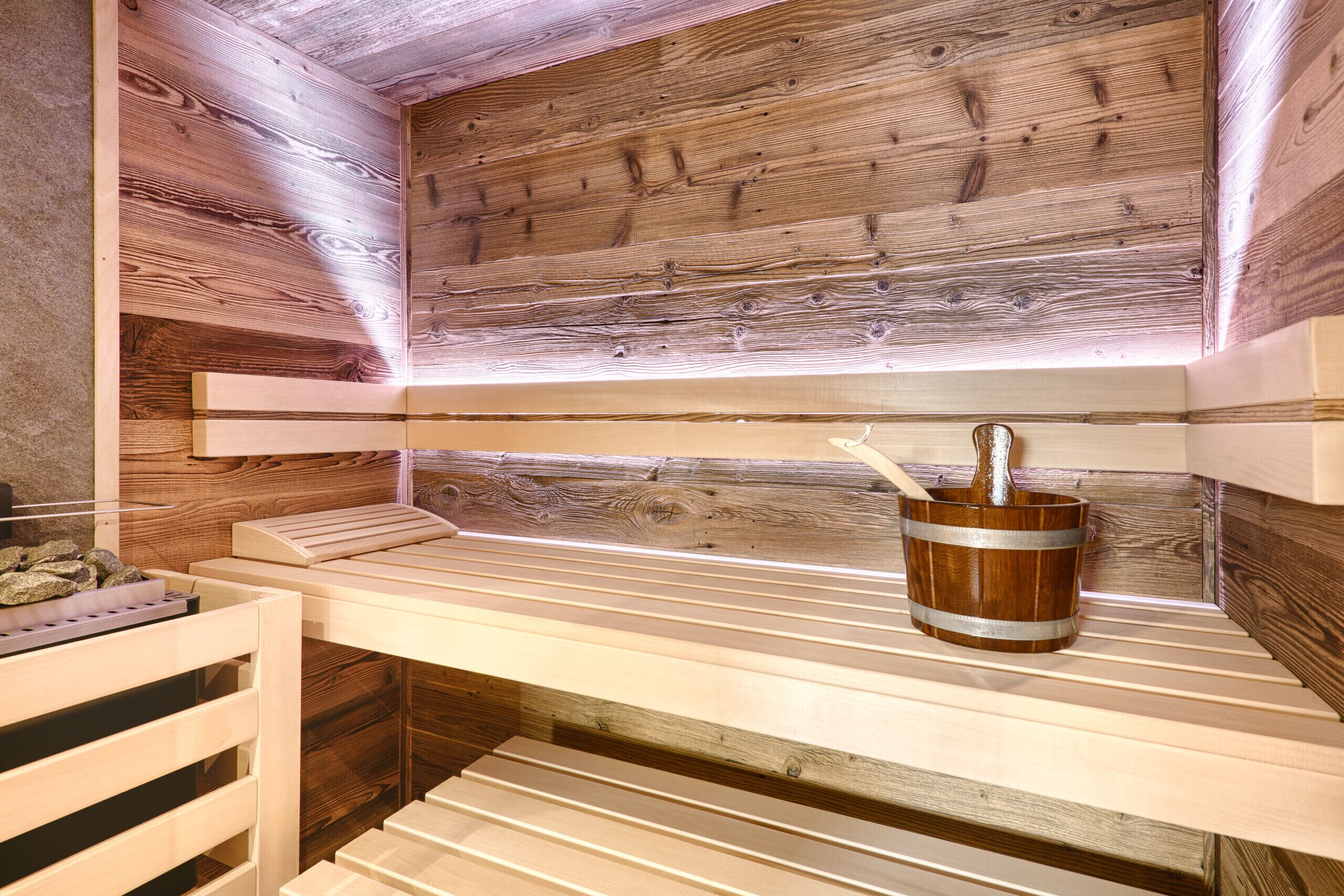 Eine Holzsauna mit Bänken und einem Eimer mit einer Flasche.