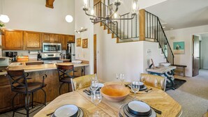 Une cuisine moderne avec des meubles en bois, un îlot central et un coin repas comprenant une grande table et des chaises en bois.