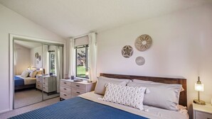 Une chambre à coucher avec un grand lit, une commode, un miroir et une table de chevet avec une lampe.