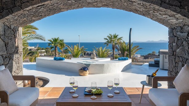 A stone archway overlooking a pool area with a view of the sea.
