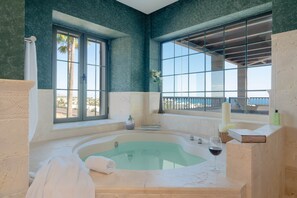 Une salle de bain avec une baignoire, une fenĂȘtre, une serviette, un verre de vin et un livre.