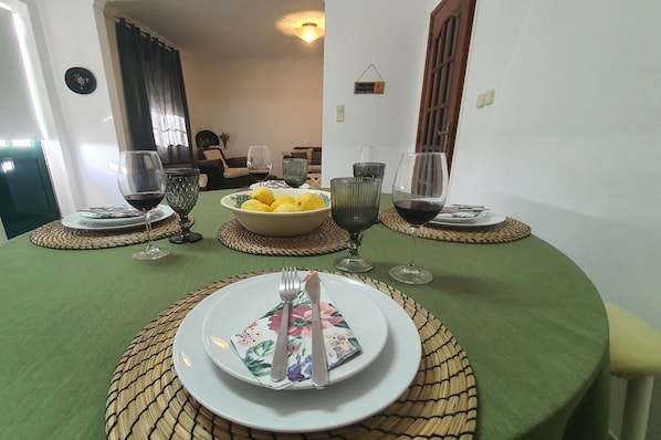 A dining table set with plates, cutlery, glasses, and a bowl of lemons.