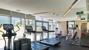 A gym with treadmills, elliptical machines, and weight equipment. - Majestine Stylish Studio with Canal View (Dubai)