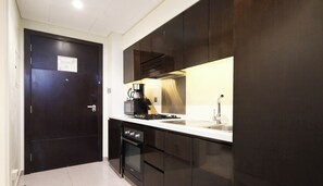 A modern kitchen with dark cabinetry, a stainless steel sink, and a coffee maker.