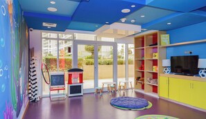 A brightly colored children's playroom with a large window, a television, and various toys and furniture.