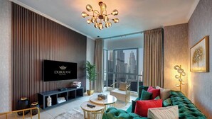 Een moderne woonkamer met een grote flatscreen televisie, een groene gestofte bank, een ronde salontafel en een stadszicht door grote ramen.