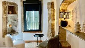 A cozy room with a stone fireplace, a small round table, and a comfortable chair. - Le Clos du Vialle (Grillon)