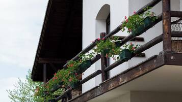 Un chalet traditionnel doté d’un balcon en bois, d’un mur en pierre et d’une clôture en bois.