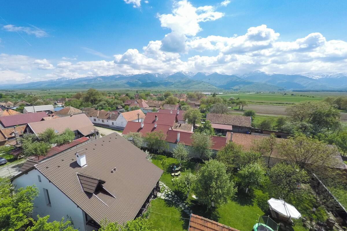 A rural village with traditional houses, a clear sky, and mountains in the background.