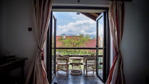 Een balkon met rieten meubilair en uitzicht op gebouwen en bergen.