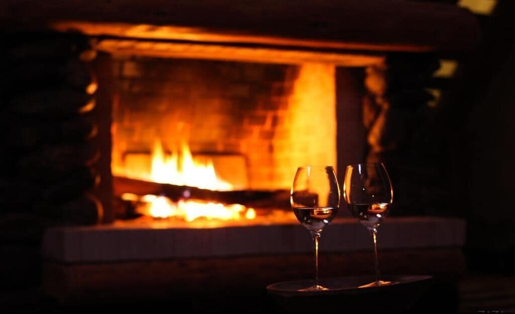 Dos copas de vino frente a una chimenea.