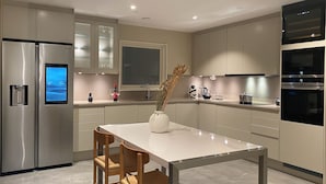 A modern kitchen with stainless steel appliances, a marble countertop, and a dining area with wooden chairs. - Exclusive newly apartment with free parking (Västra Götalands län)