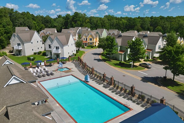 A residential area with a swimming pool, houses, and a road.