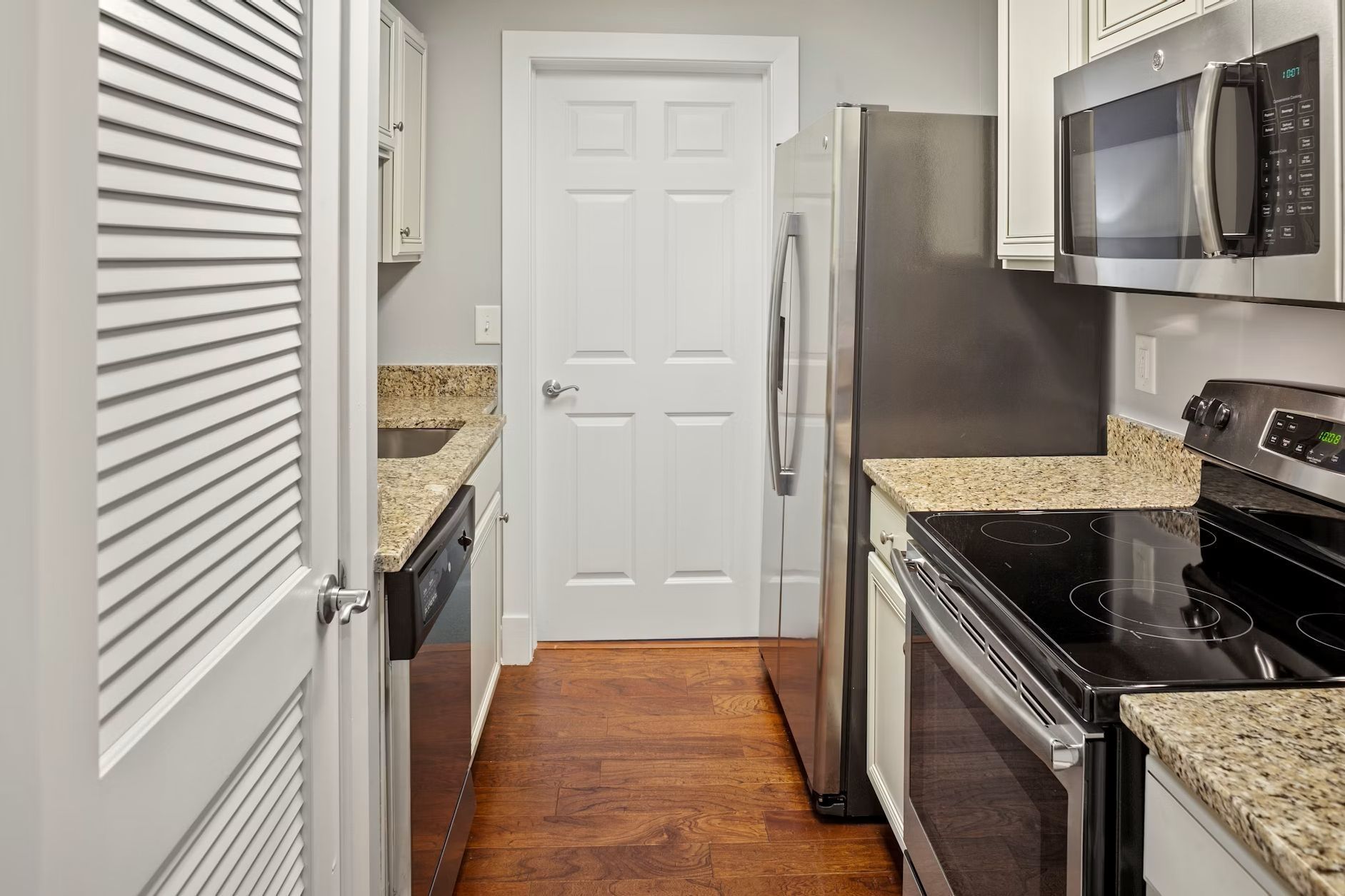 A kitchen with a stainless steel refrigerator, a microwave, an oven, and a dishwasher.