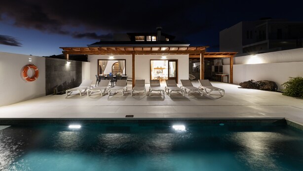 A modern outdoor pool area with lounge chairs and a covered seating area.